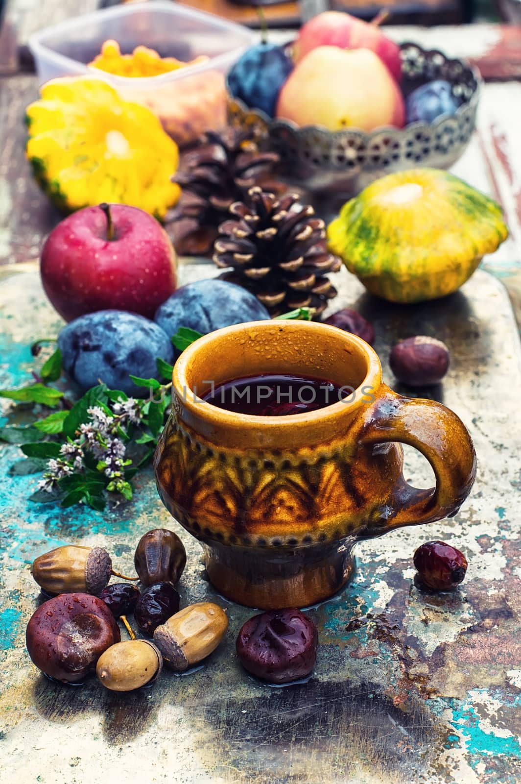 Stylish cup of autumn tea infused with herbs on the background of the fruit