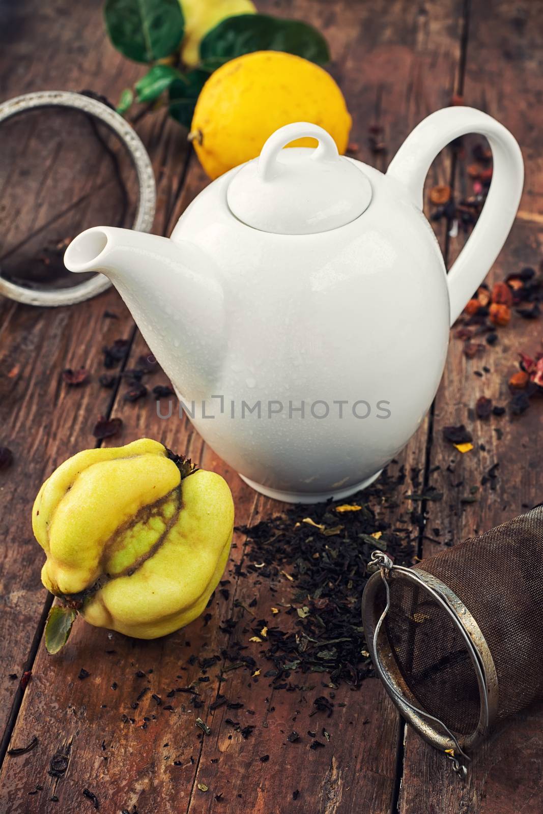 White teapot on  background of quince fruit and spilled tea