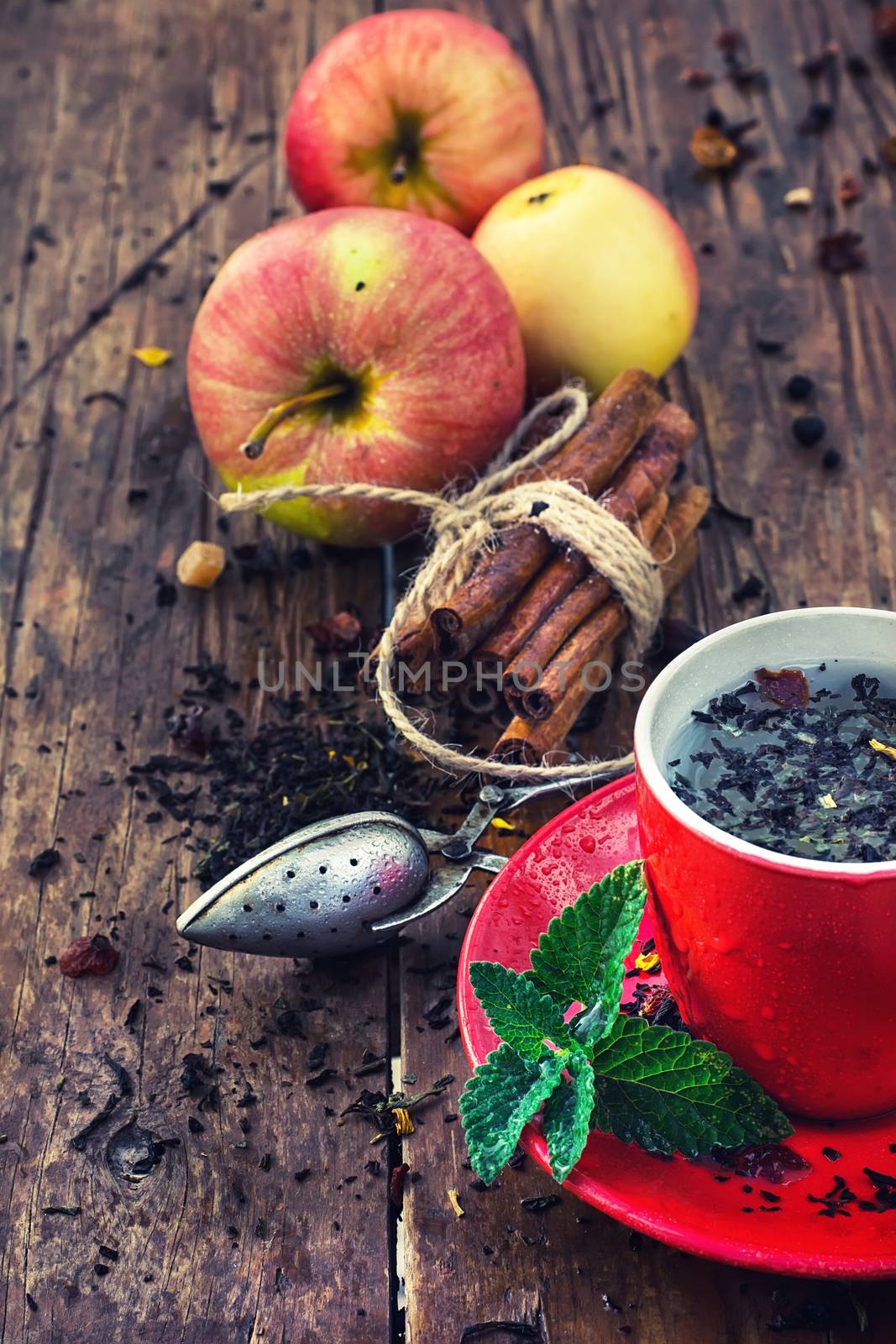 Red Cup and saucer of herbal tea with apples and cinnamon sticks