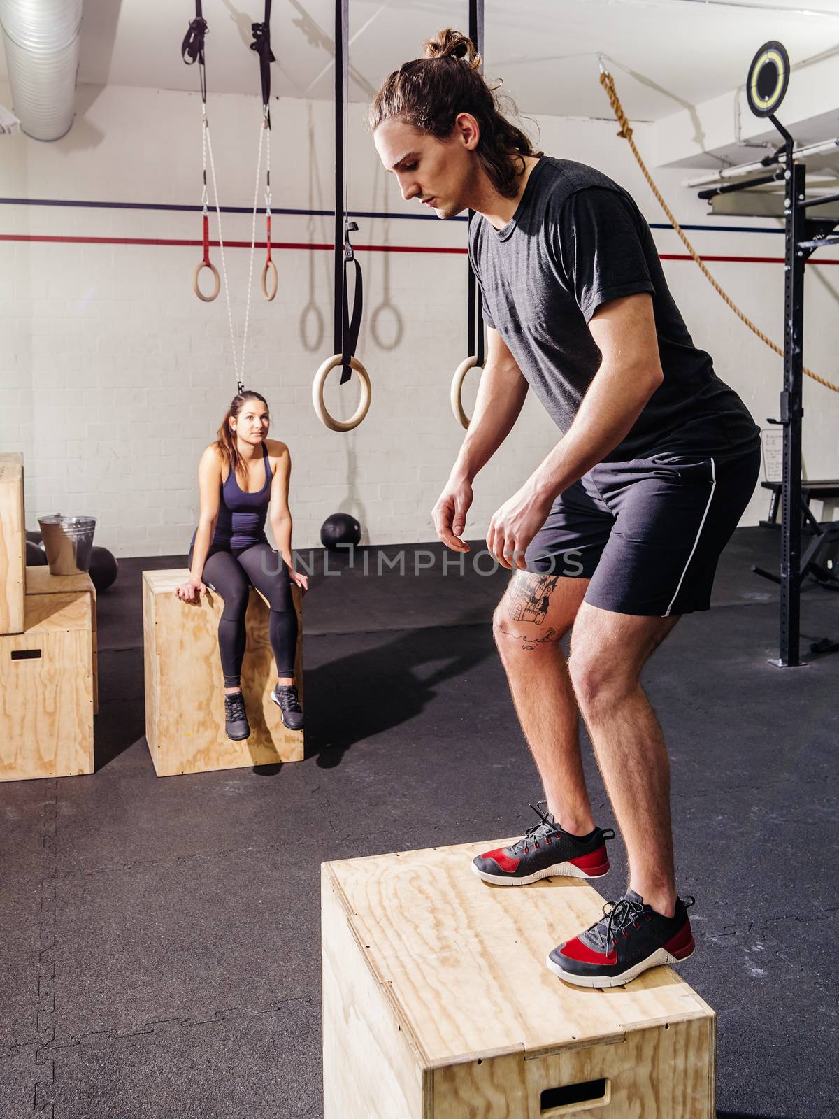 Photo of an attractive young woman and man working out doing jumps at a crossfit gym.