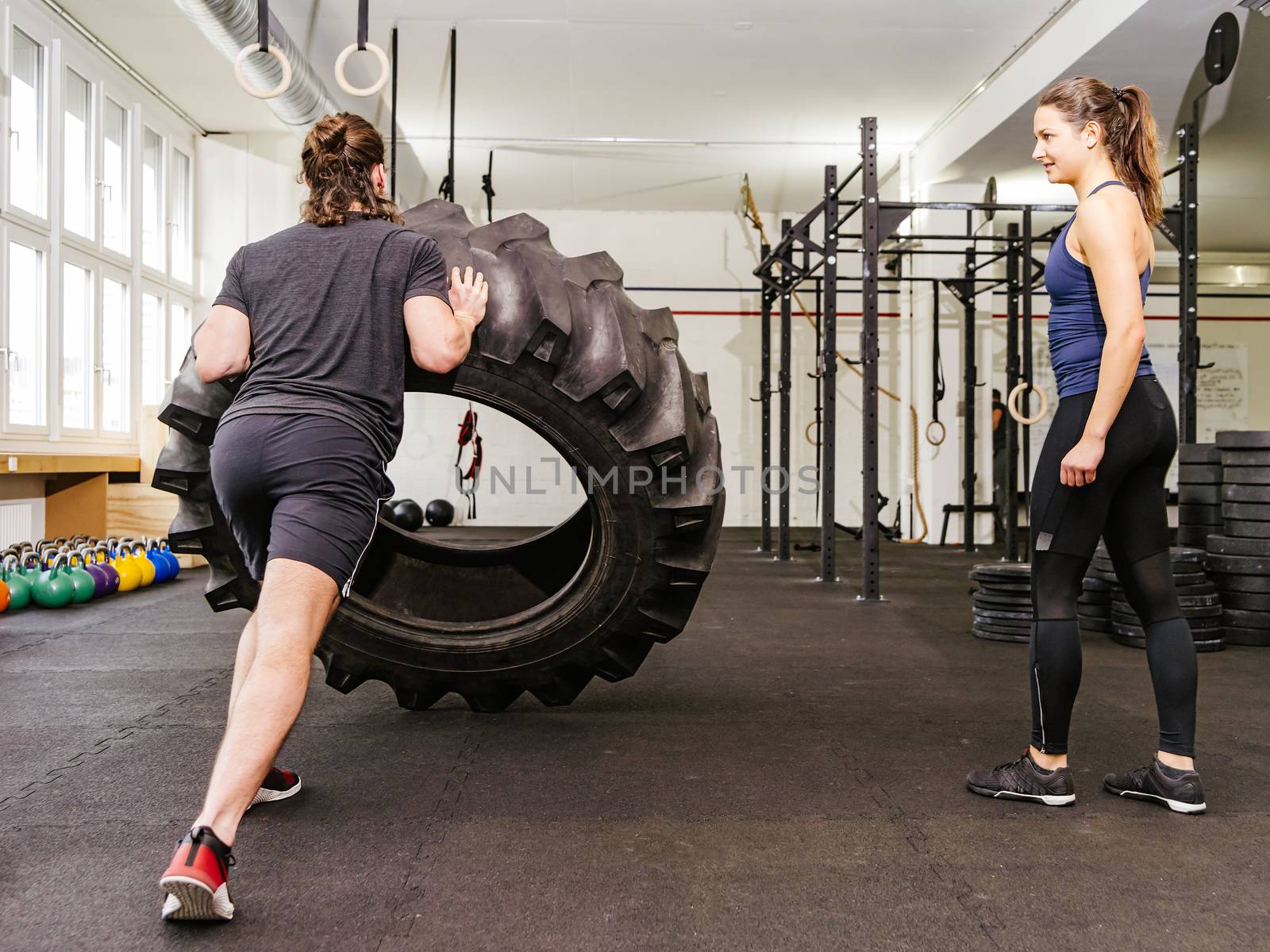 Couple working out with tire at crossfit gym by sumners