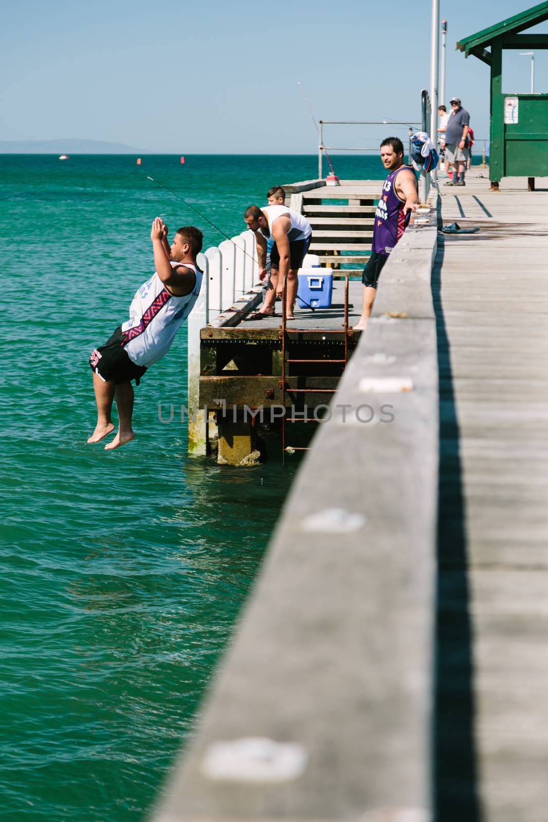 MELBOURNE/AUSTRALIA - FEBRUARY 6: Youths jump off a jetty into the water, while others fish in Mordialloc, a coastal suburb of Melbourne, Australia in February.