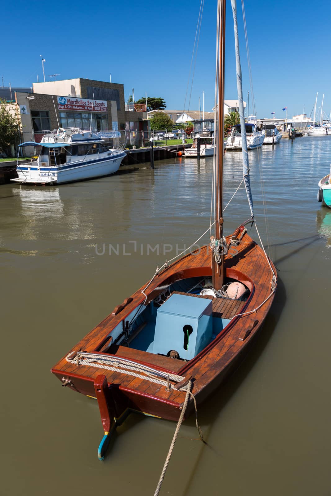 a newly restored vintage wooden sailboat moured at a small marina in Melbourne.