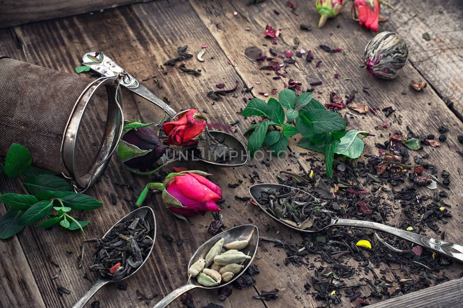 Stylish spoons with  variety of tea on vintage wooden board.