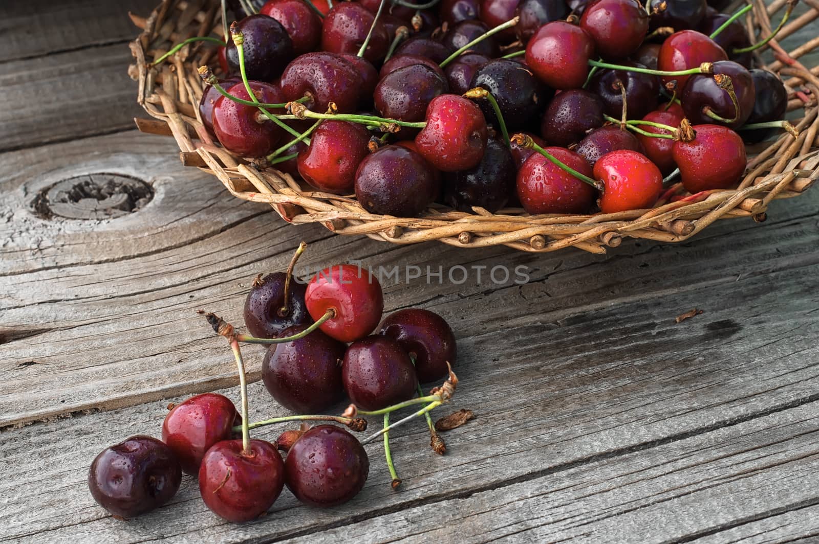 Ripe cherries on wooden background in a wicker basket