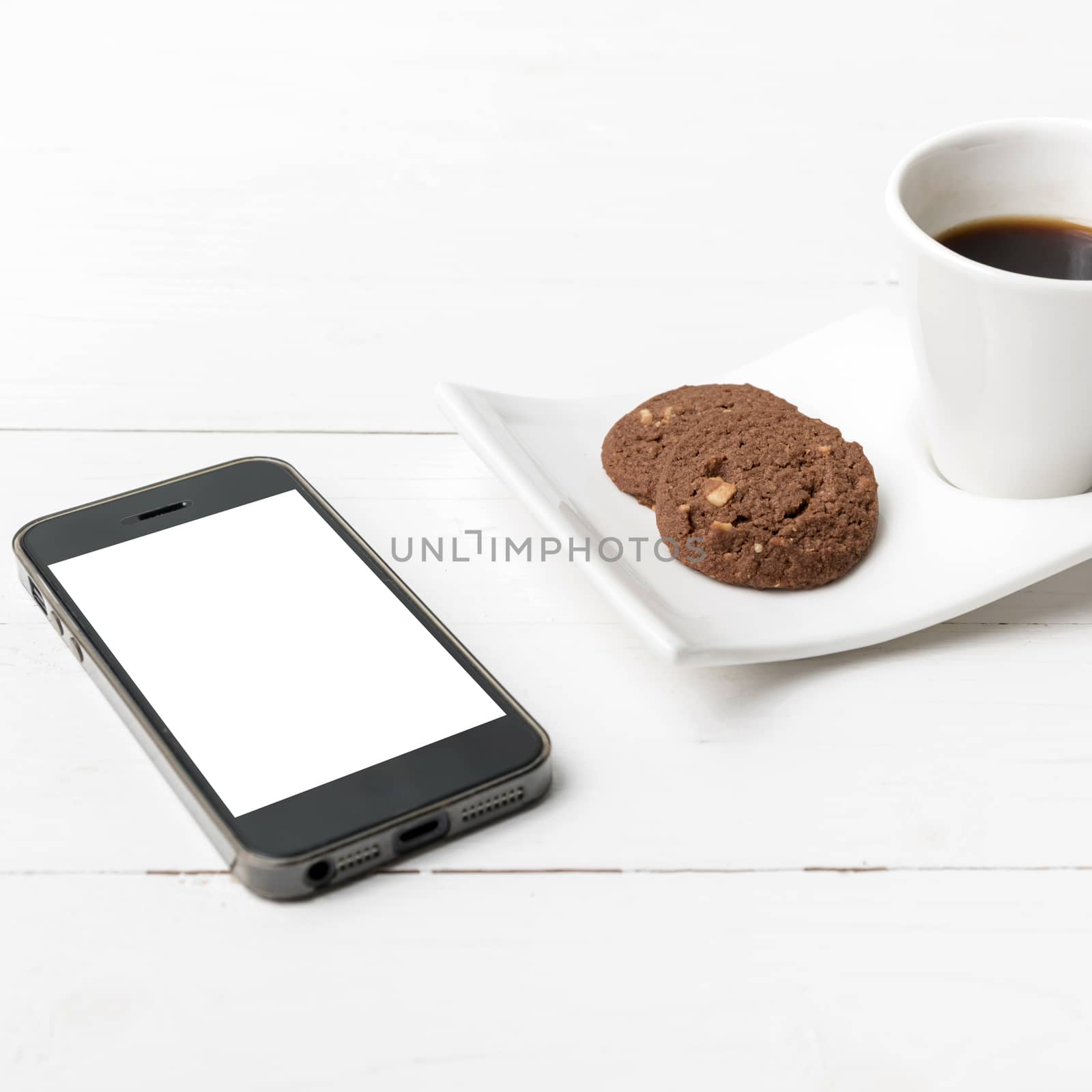 coffee cup with cookie and phone on white wood background