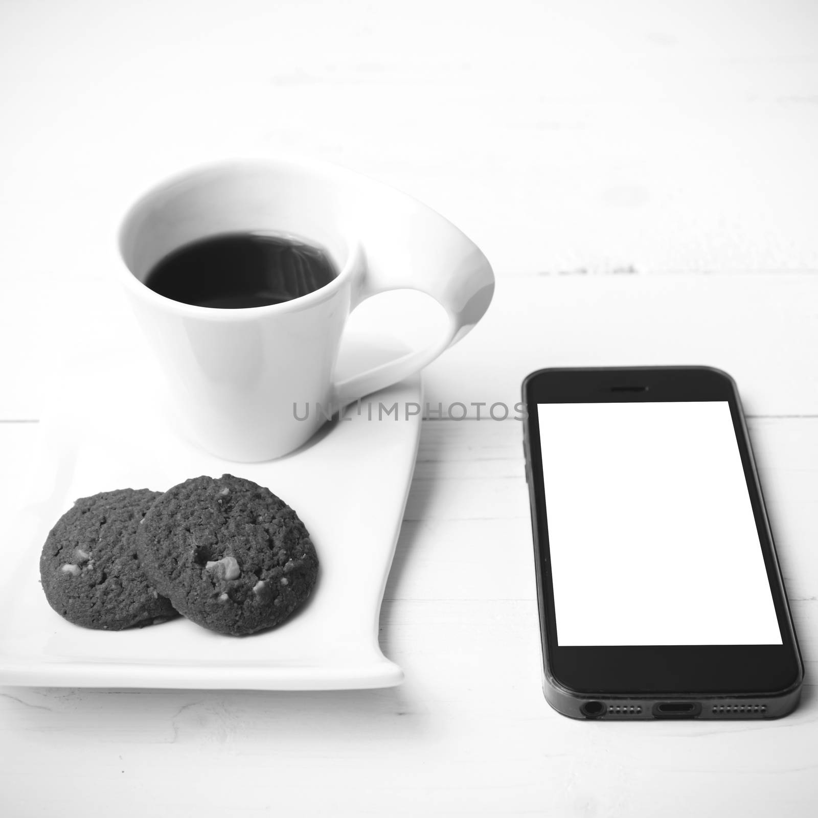 coffee cup with cookie and phone on white wood black and white color