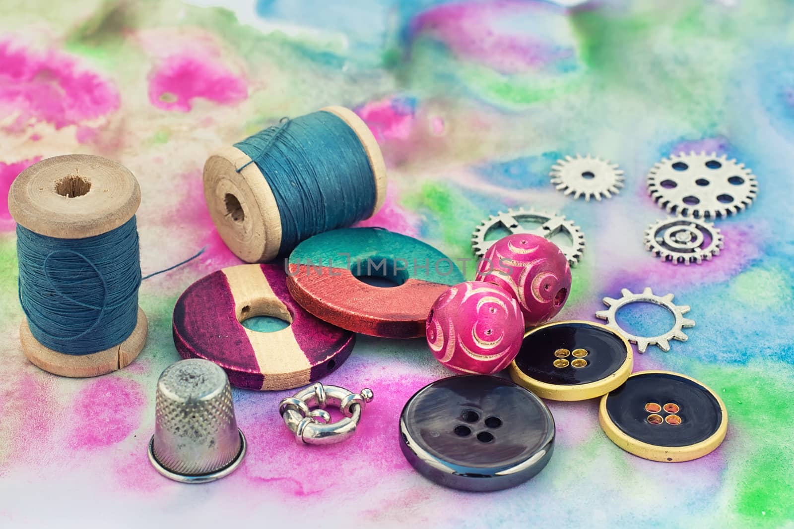 spool of thread with beads and accessories for needlework on bright background