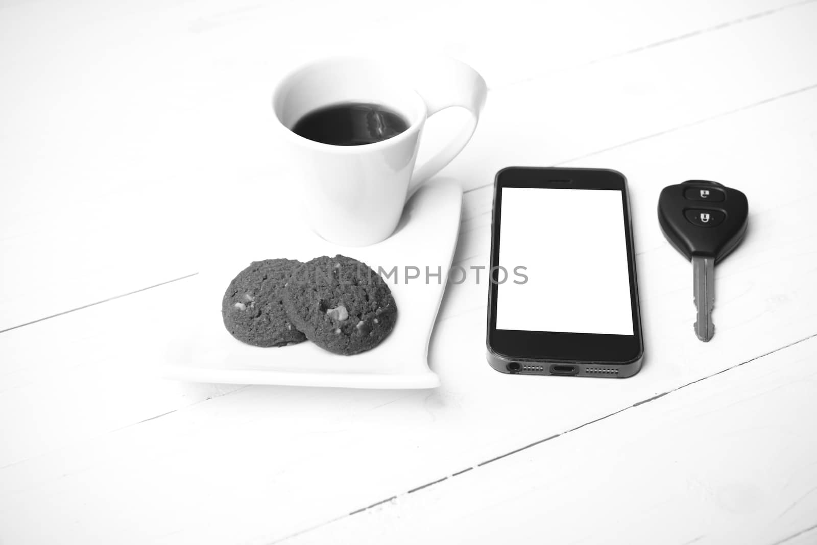 coffee cup with cookie,phone and car key on white wood table black and white color