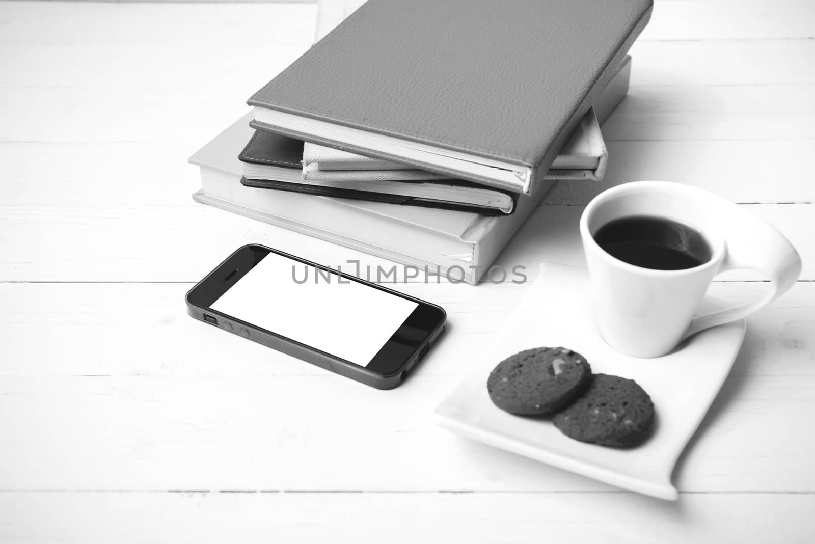 coffe cup with cookie,phone and stack of book on white wood table black and white color