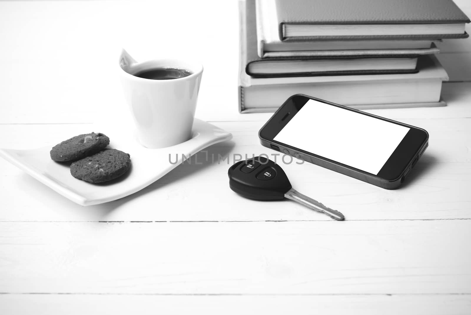 coffe cup with cookie,phone,car key and stack of book on white wood table black and white color