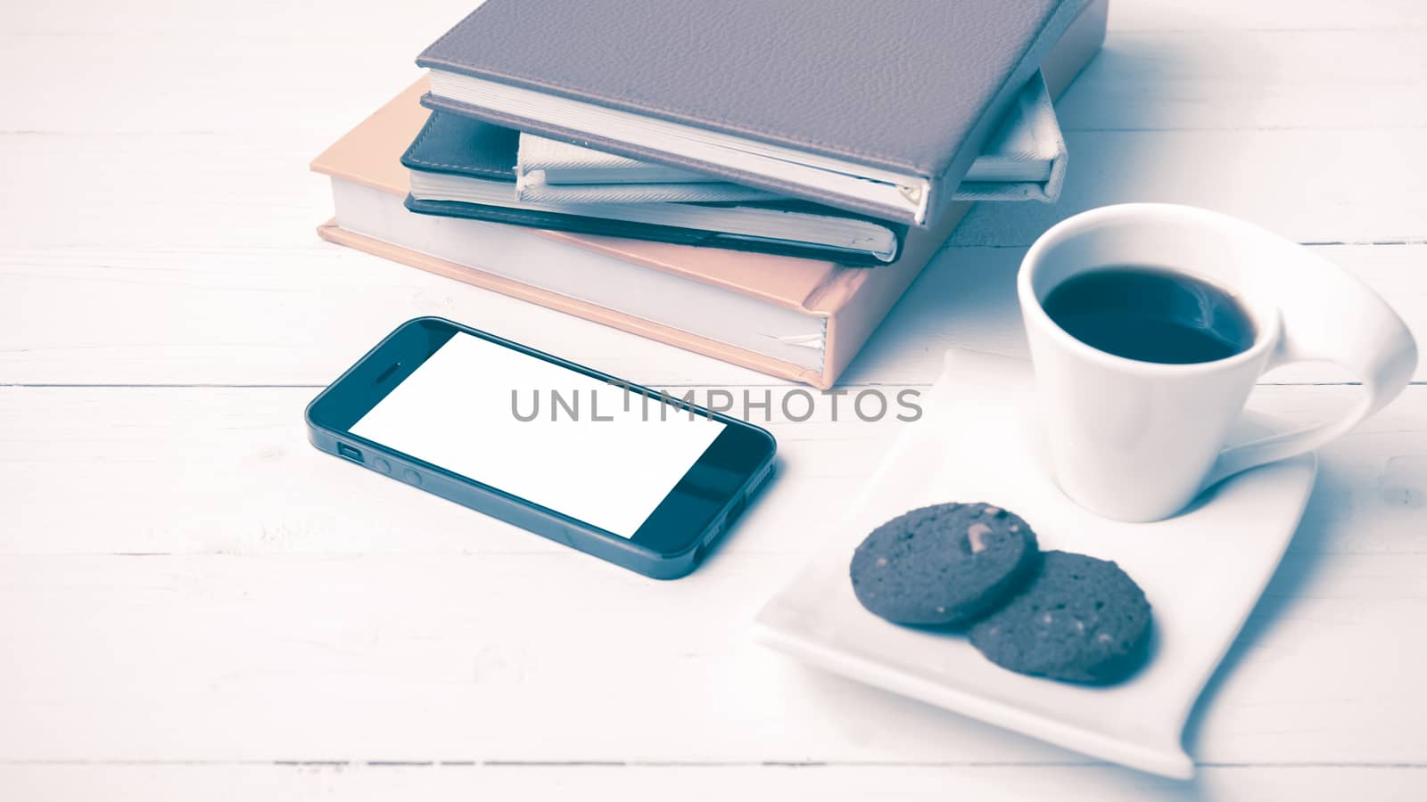 coffe cup with cookie,phone and stack of book on white wood table vintage style