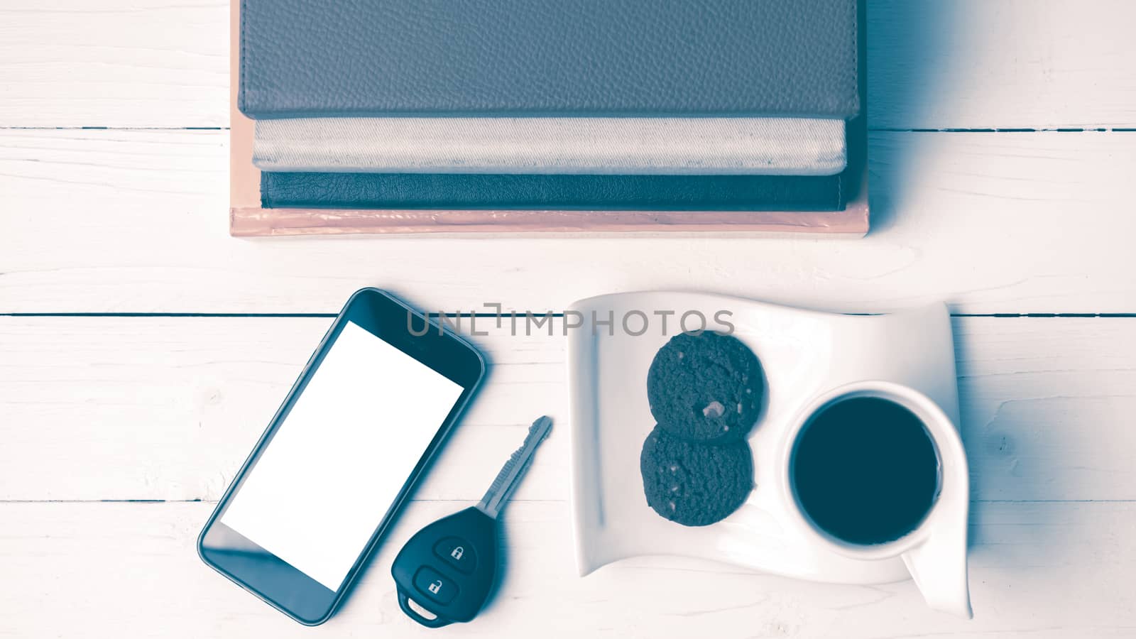 coffe cup with cookie,phone,car key and stack of book on white wood table vintage style