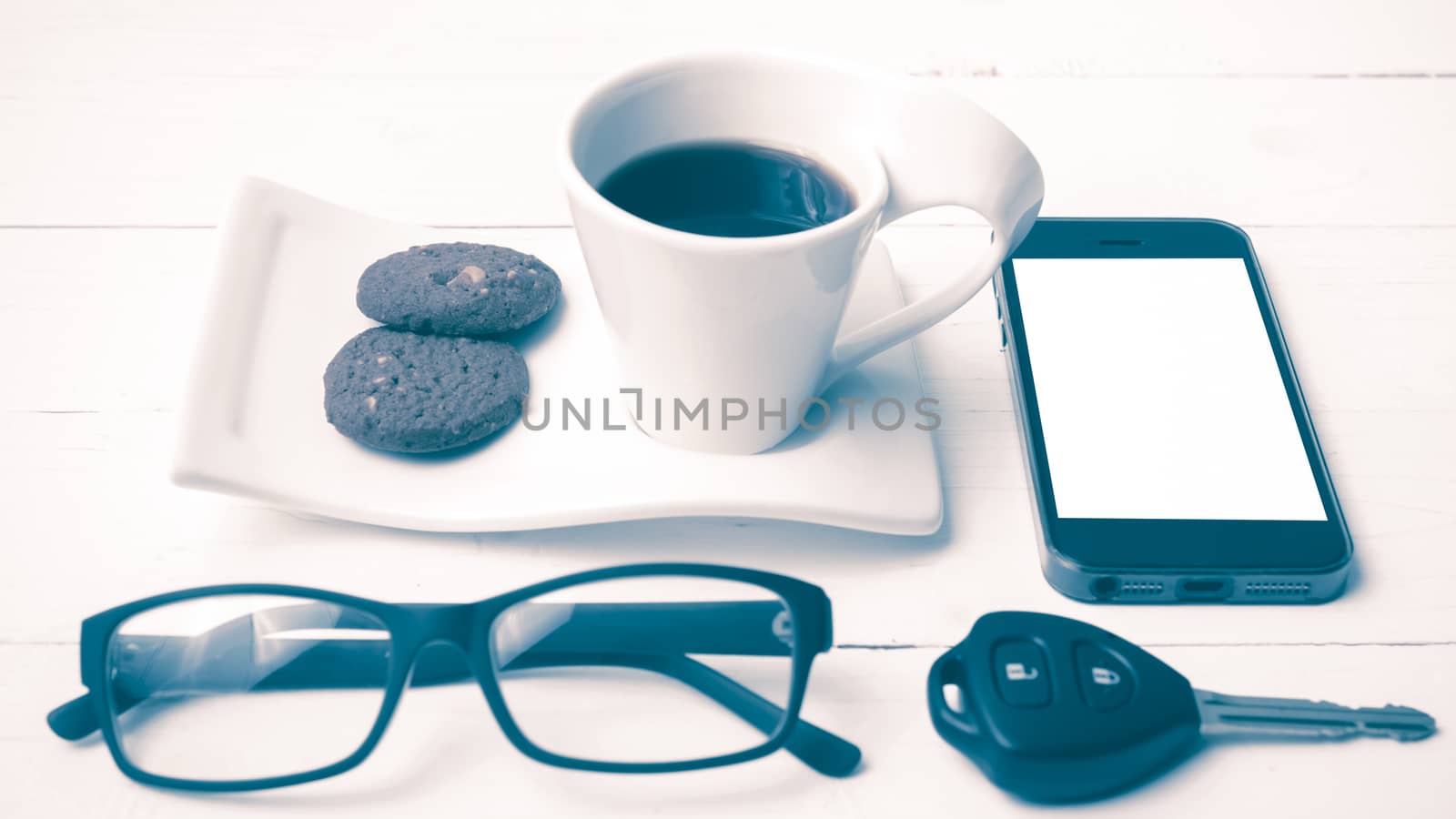 coffee cup with cookie,phone,eyeglasses and car key on white wood table vintage style