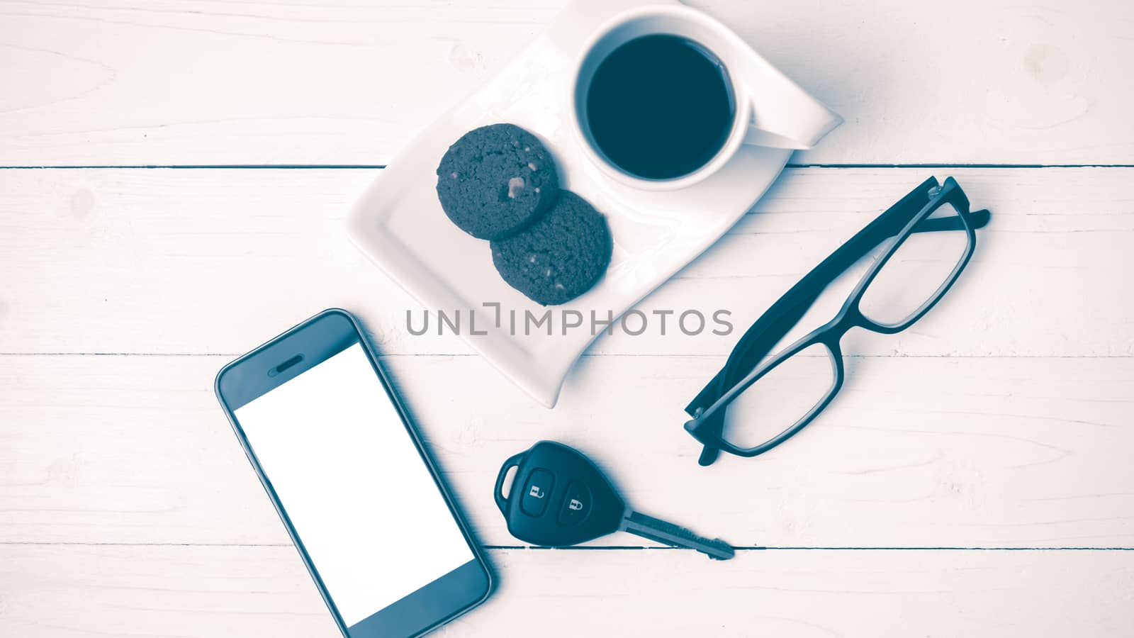 coffee cup with cookie,phone,eyeglasses and car key on white wood table vintage style