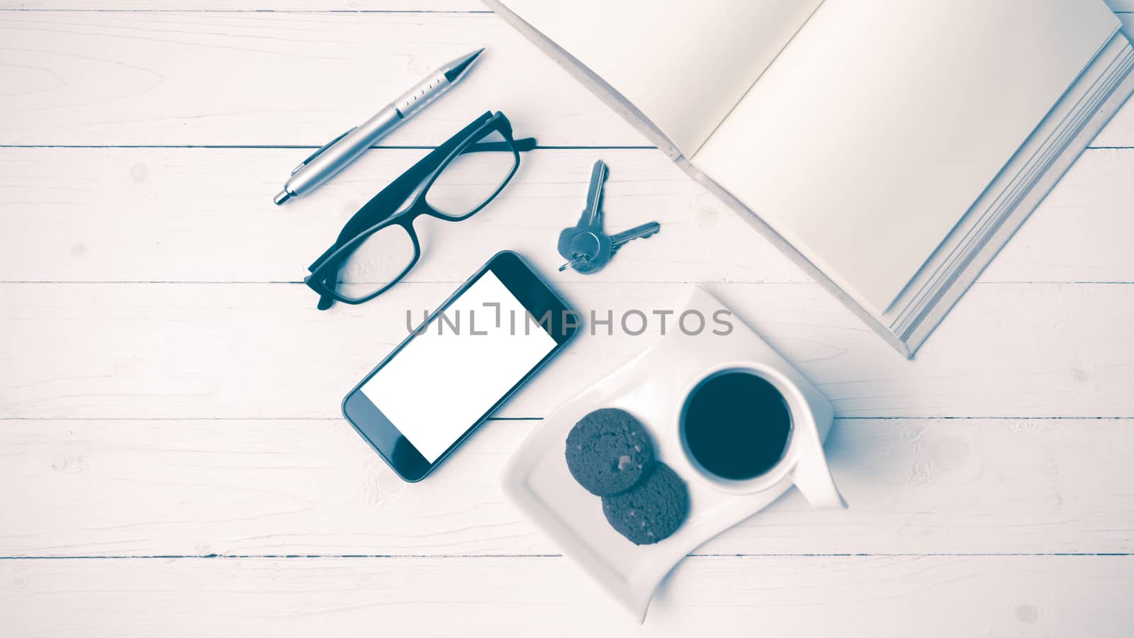 coffee cup with cookie,phone,open notebook and eyeglasses on white wood table vintage style