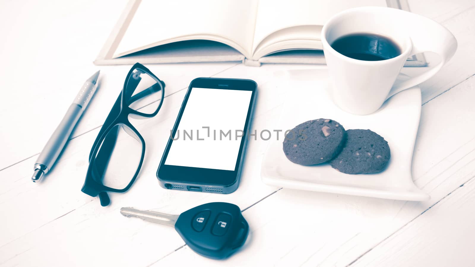 coffee cup with cookie,phone,open notebook,car key and eyeglasses on white wood table vintage style