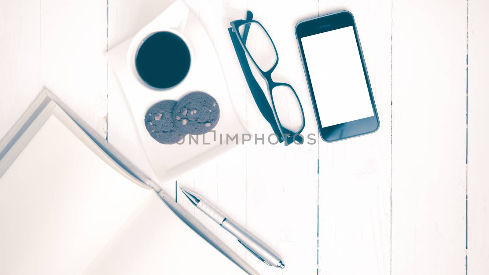 coffee cup with cookie,phone,notebook and eyeglasses on white wood table vintage style