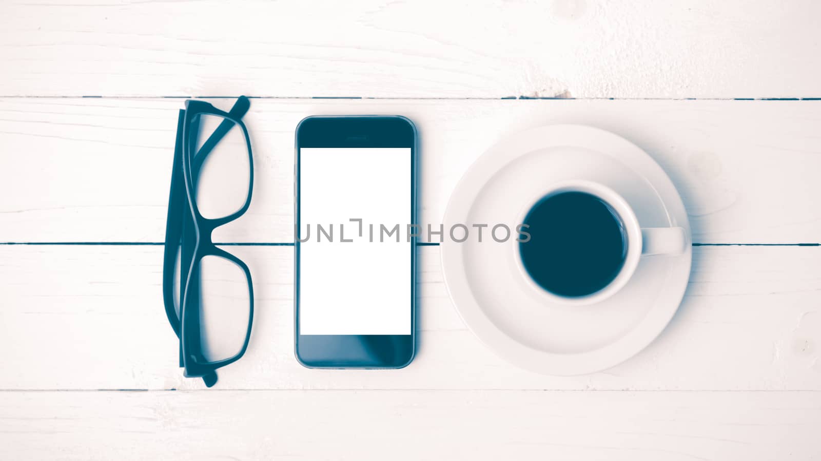coffee cup with phone and eyeglasses on white wood table vintage style