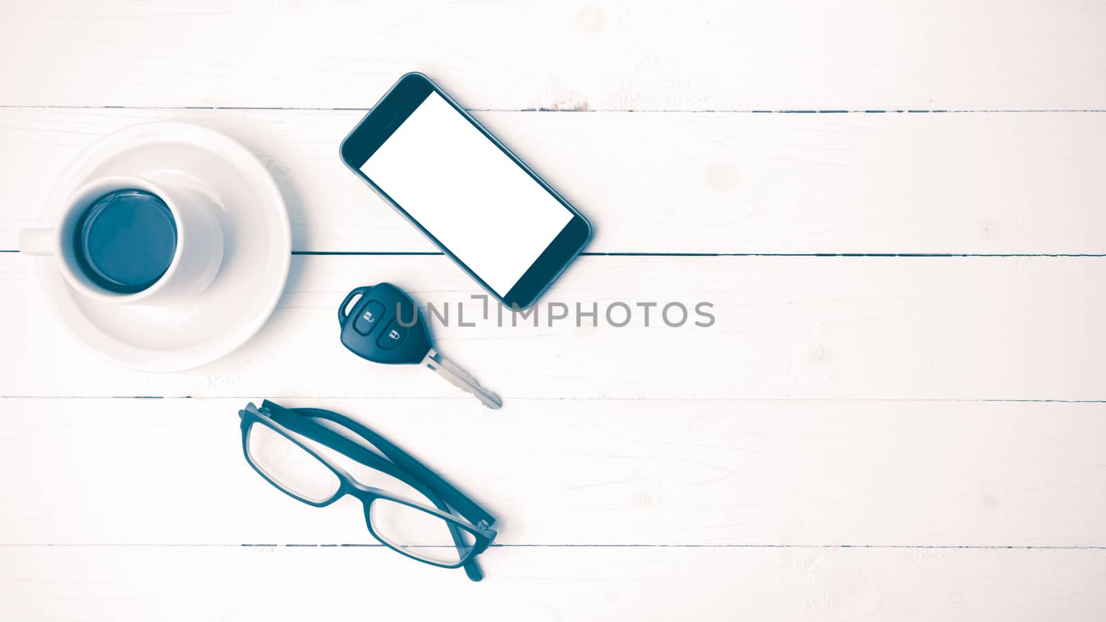 coffee cup with phone, eyeglasses and car key on white wood table vintage style