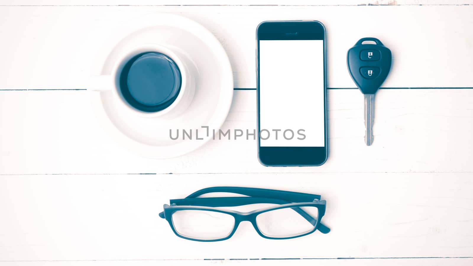 coffee cup with phone, eyeglasses and car key on white wood table vintage style