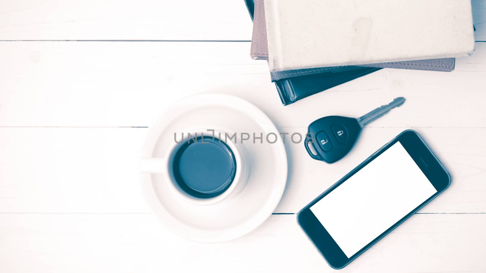 coffee cup with phone,car key and stack of book on white wood table vintage style