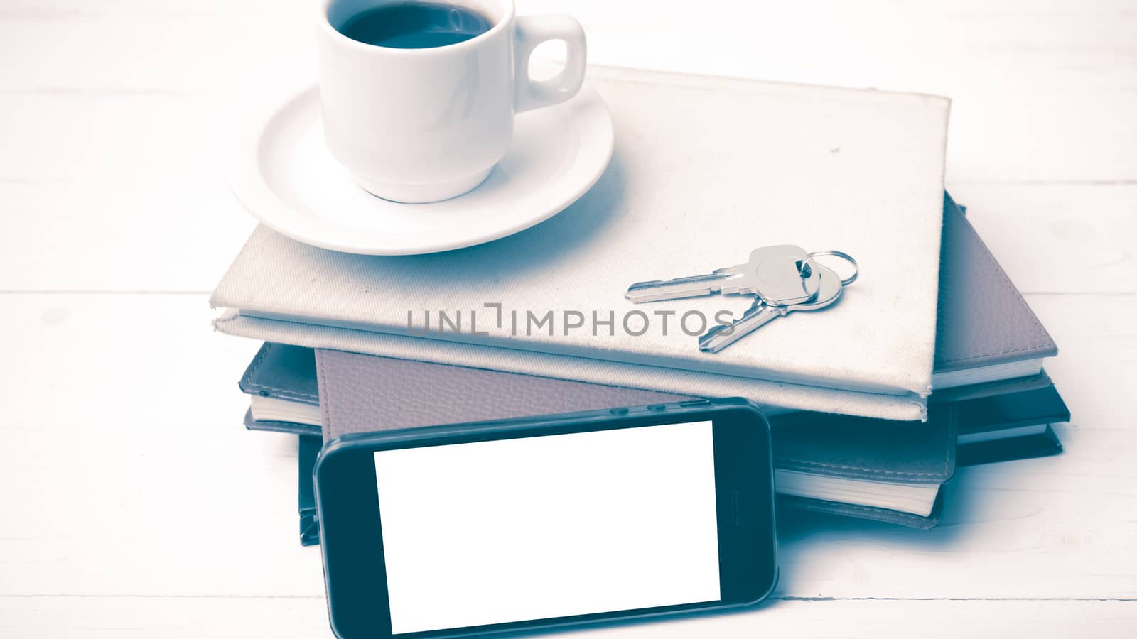 coffee cup with phone,key and stack of book on white wood table vintage style