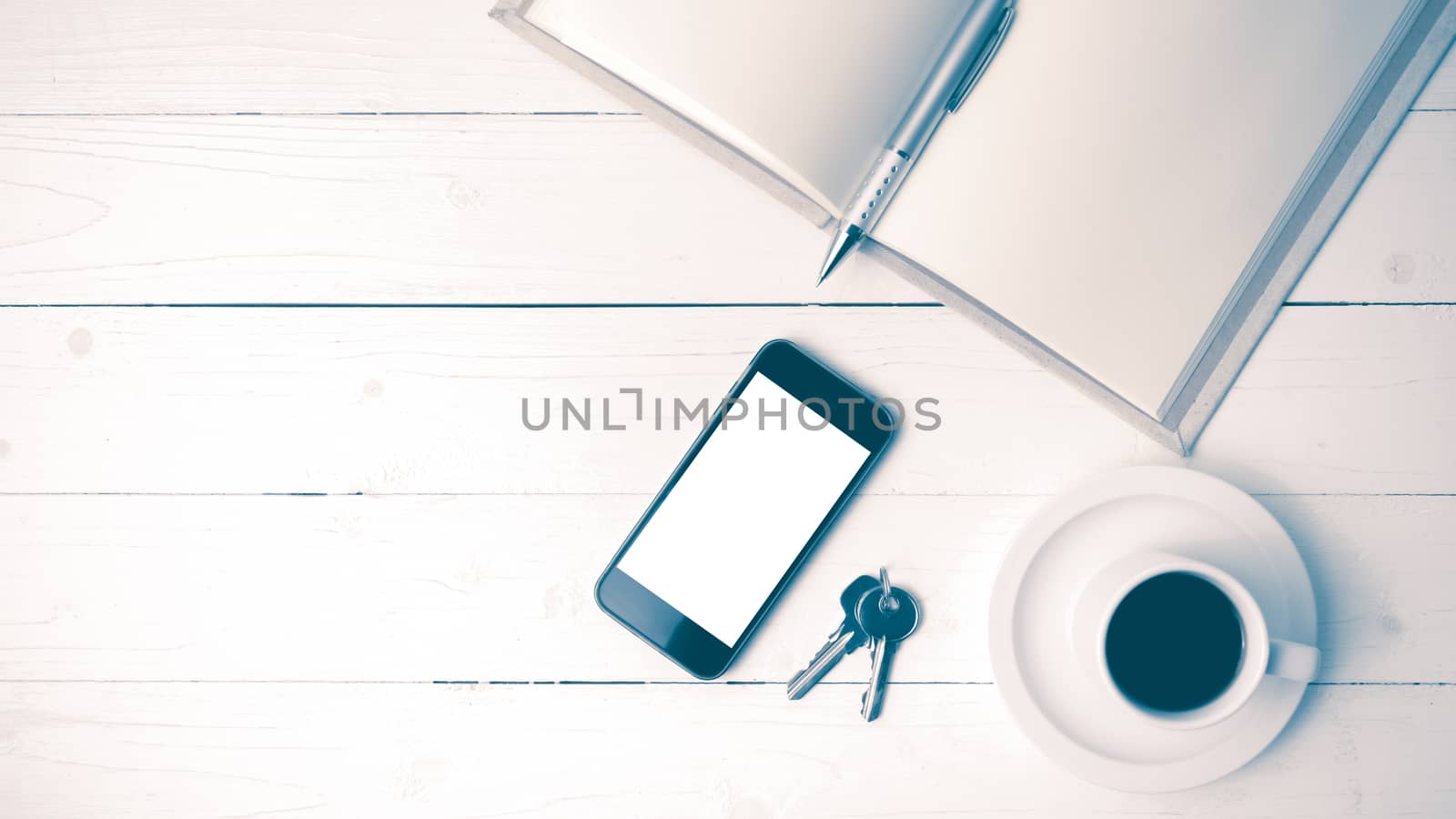 coffee cup with phone, key and open notebook on white wood table vintage style