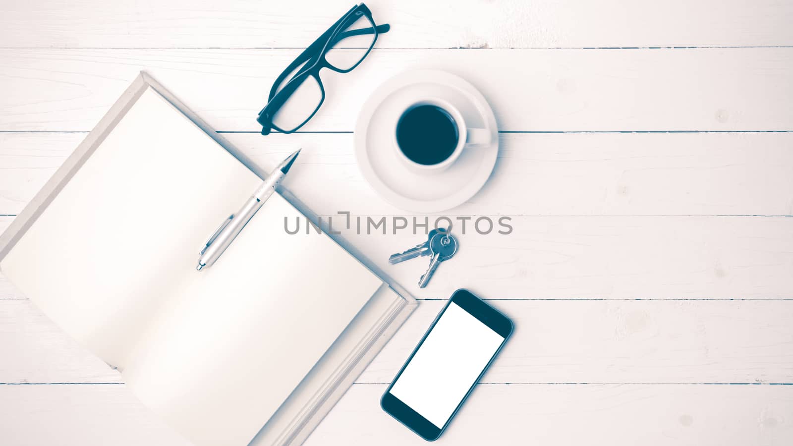 coffee cup with phone, key,eyeglasses and open notebook on white wood table vintage style