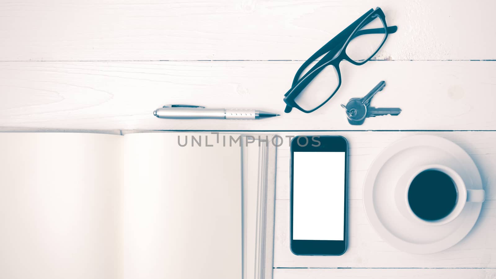 coffee cup with phone, key,eyeglasses and open notebook on white wood table vintage style