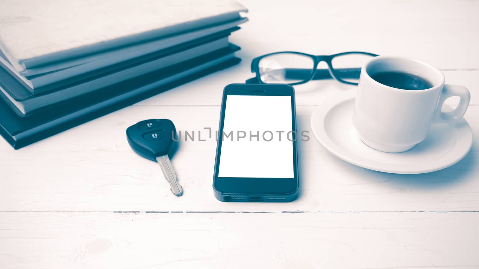 coffee cup with phone, car key,eyeglasses and stack of book on white wood table vintage style