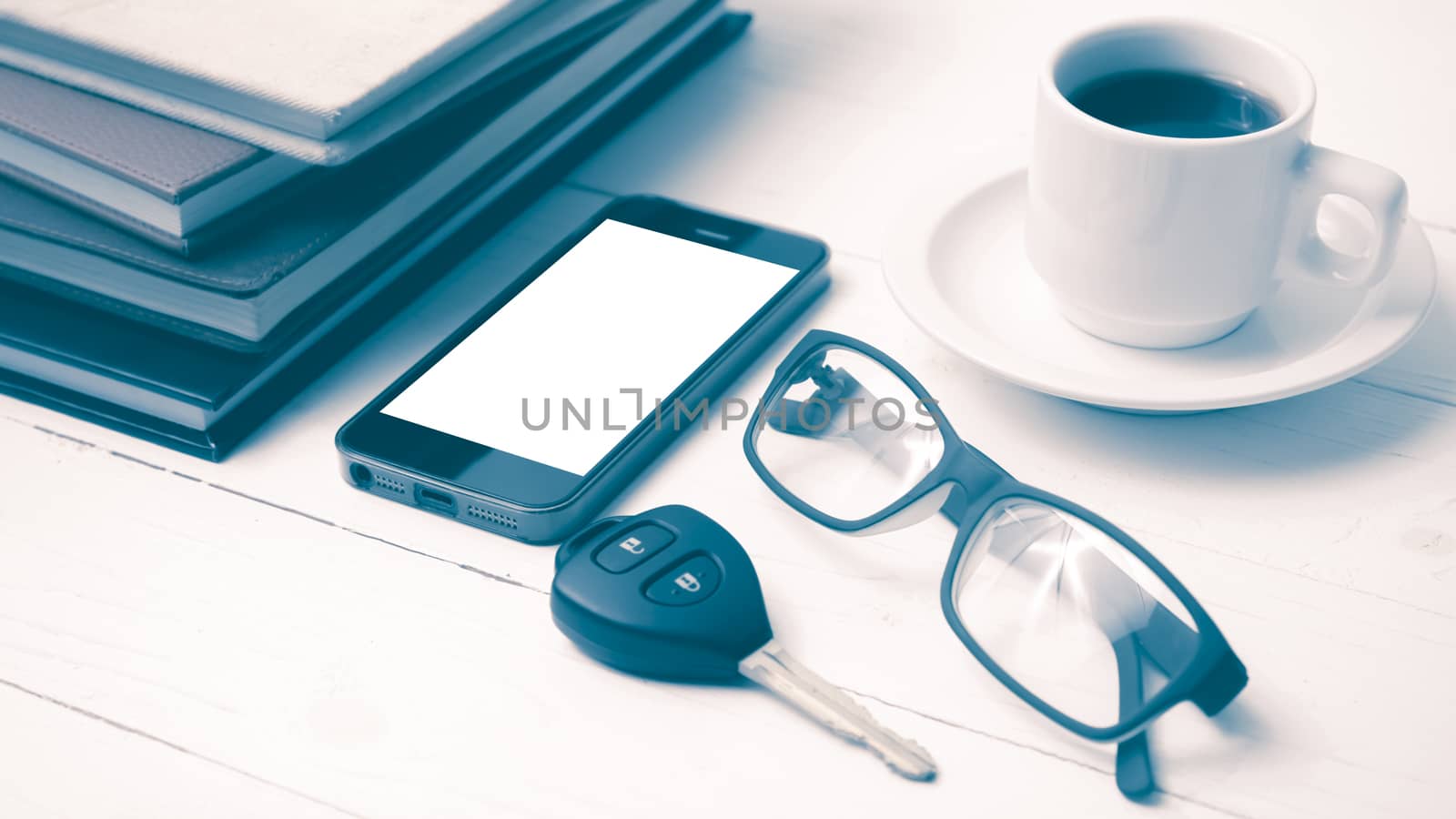 coffee cup with phone, car key,eyeglasses and stack of book on white wood table vintage style