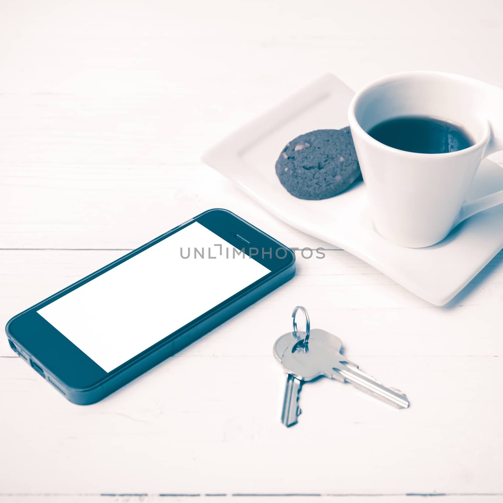 coffee cup with cookie,phone and key on white wood table vintage style
