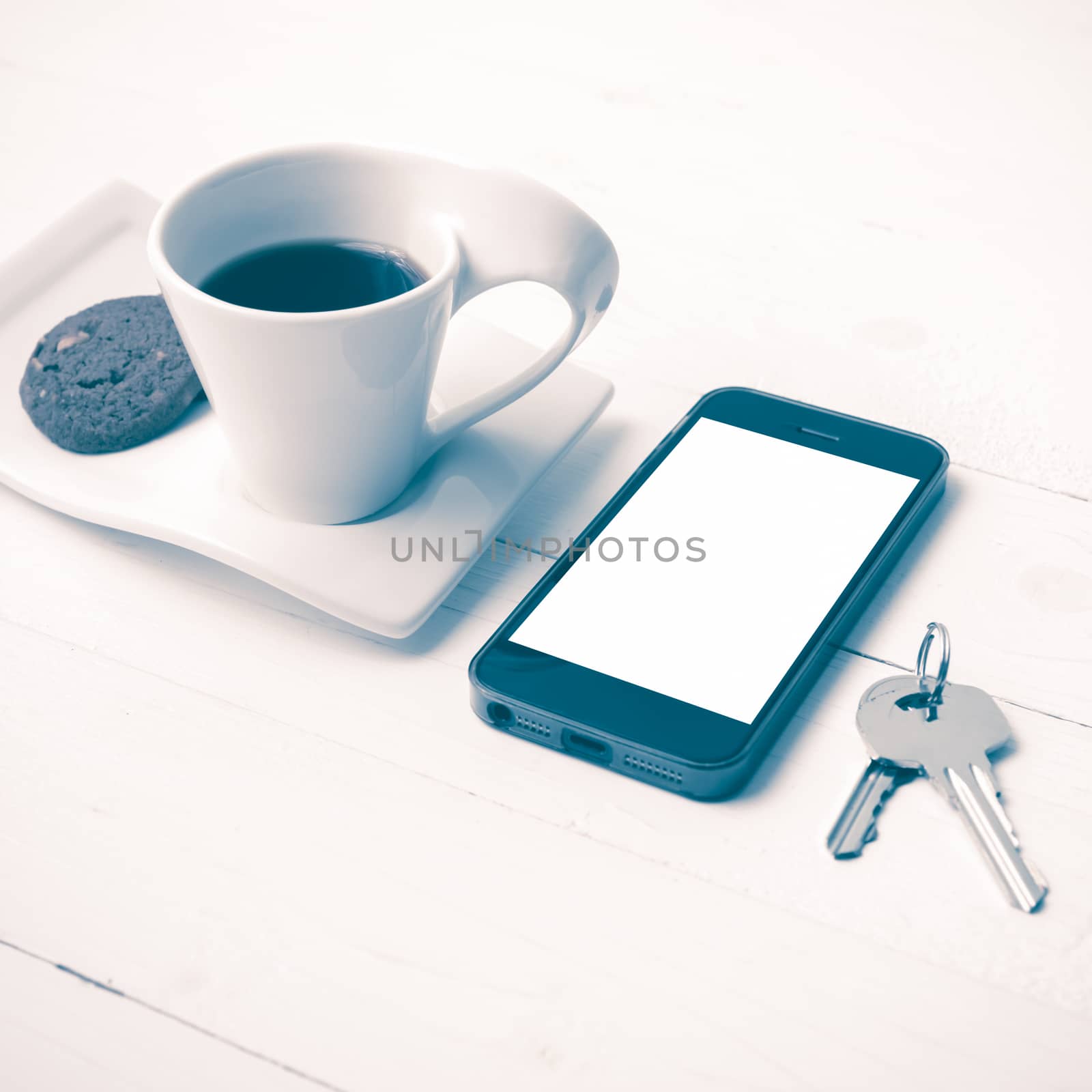 coffee cup with cookie,phone and key on white wood table vintage style