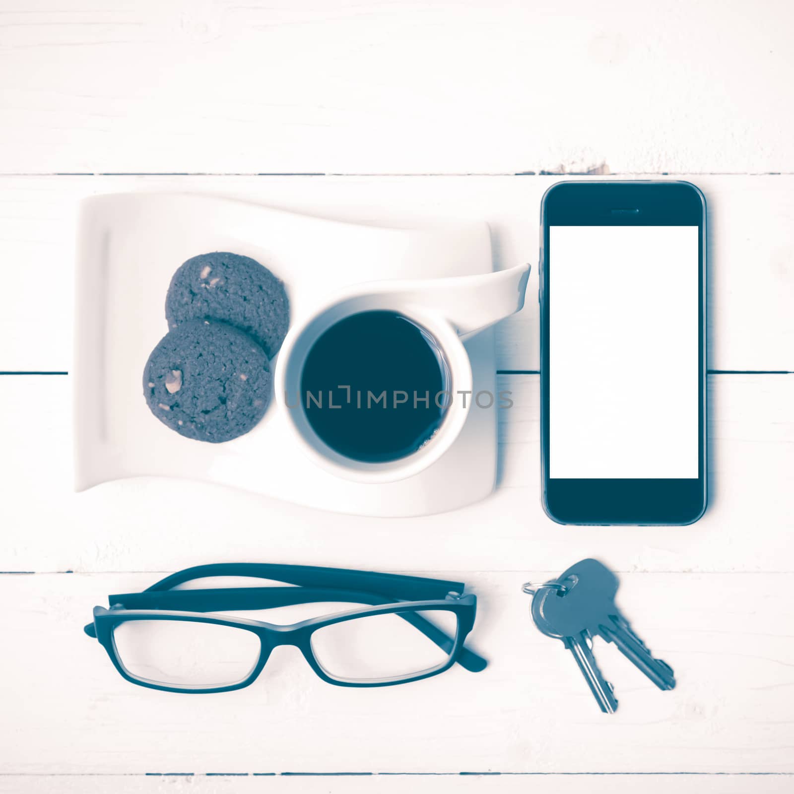 coffee cup with cookie,phone,eyeglasses and key on white wood background vintage style