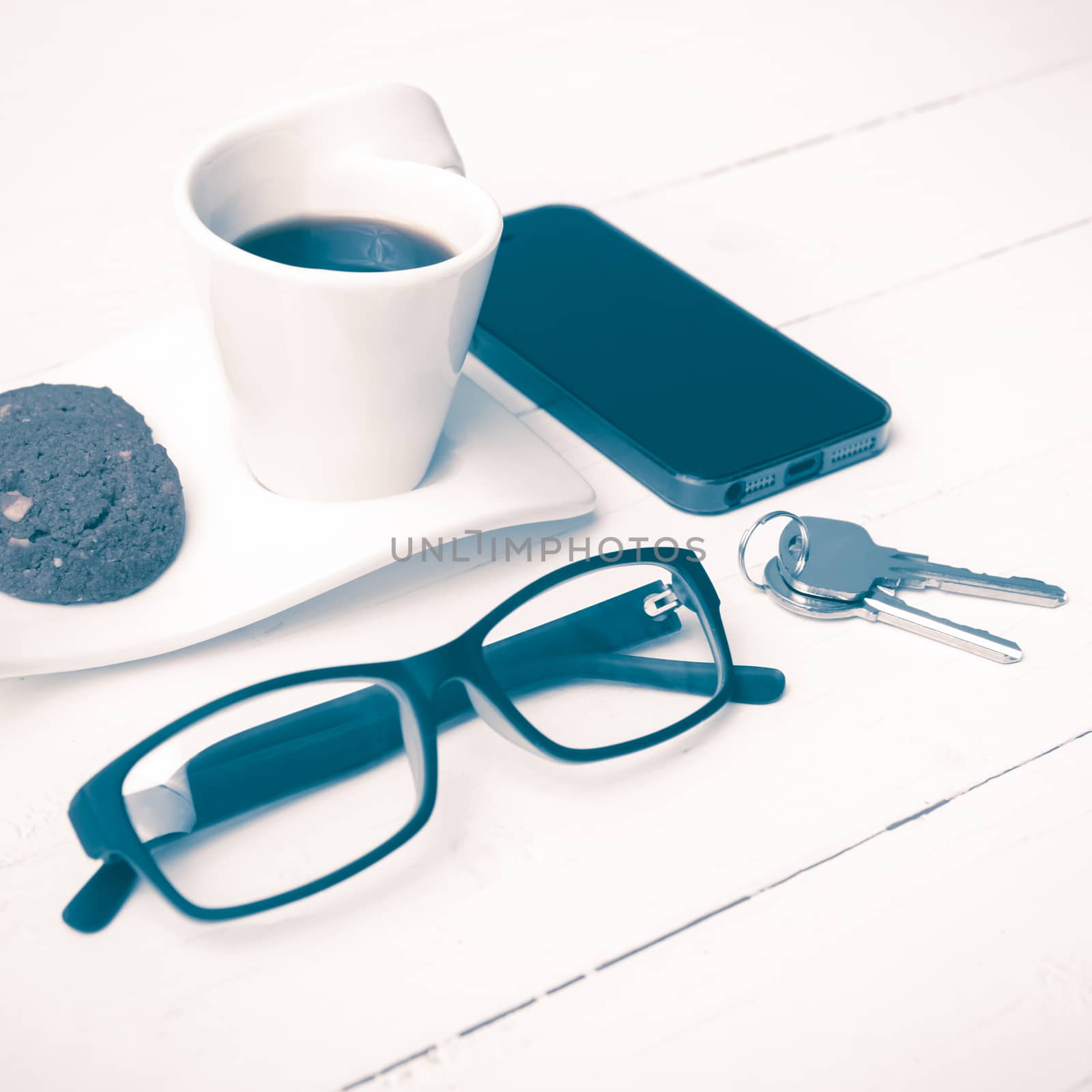 coffee cup with cookie,phone,eyeglasses and key on white wood background vintage style