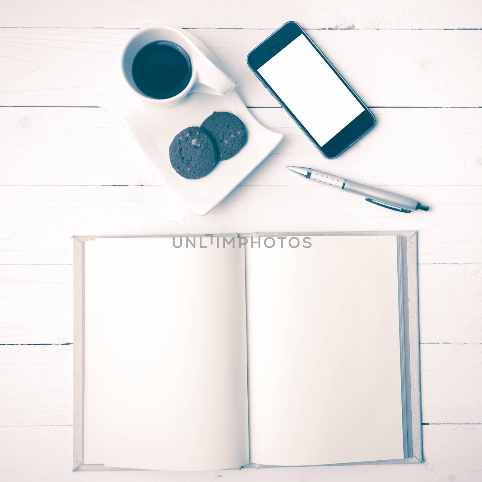 coffee cup with cookie,phone with notebook and pen on white wood table vintage style