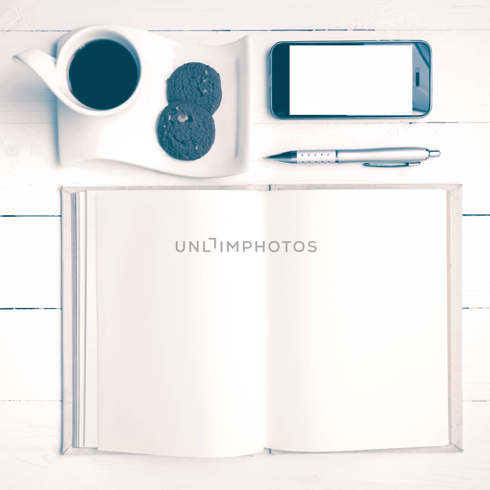 coffee cup with cookie,phone with notebook and pen on white wood table vintage style