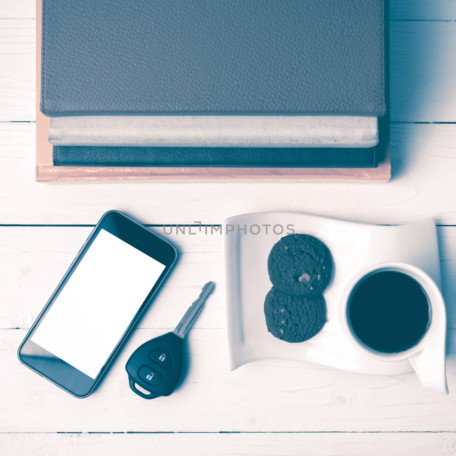 coffe cup with cookie,phone,car key and stack of book on white wood table vintage style