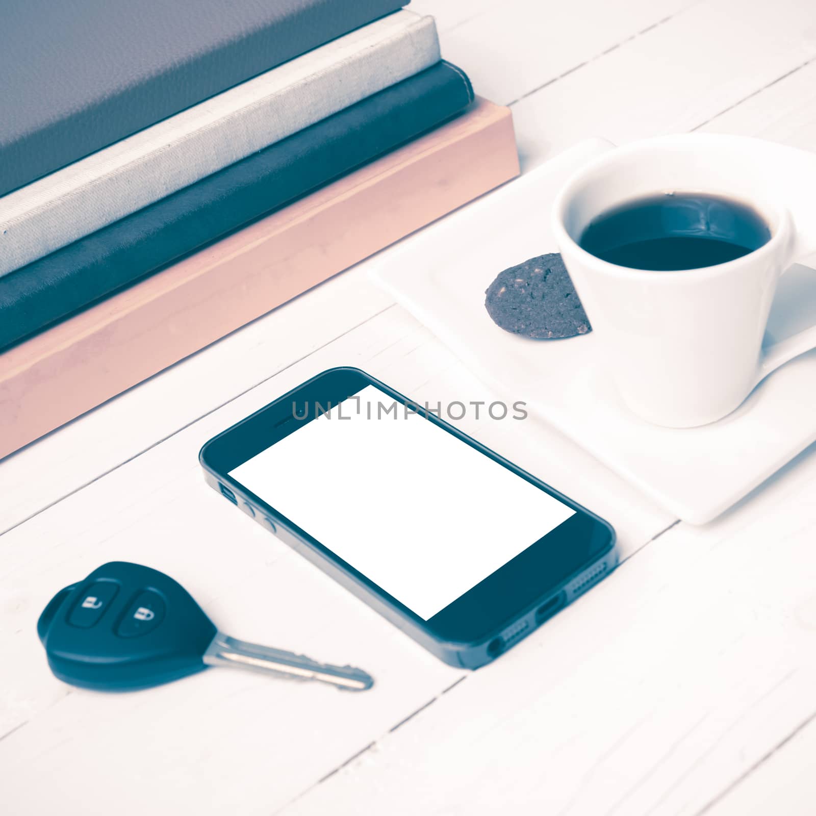 coffe cup with cookie,phone,car key and stack of book on white wood table vintage style