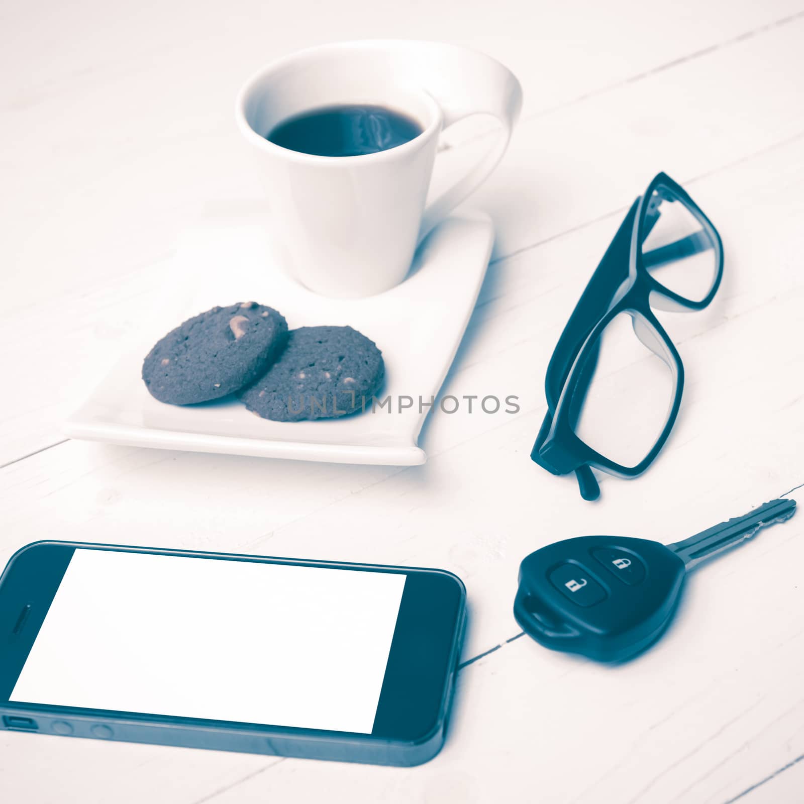 coffee cup with cookie,phone,eyeglasses and car key on white wood table vintage style