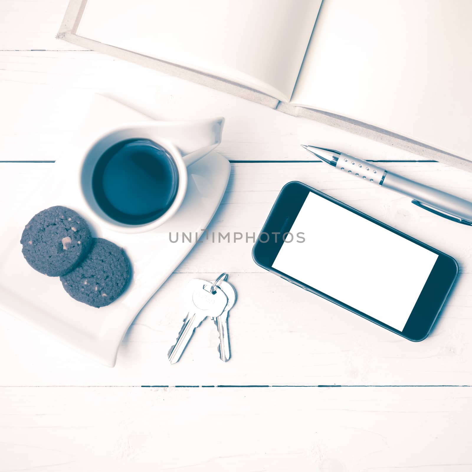 coffee cup with cookie,phone,notebook and key on white wood table vintage style