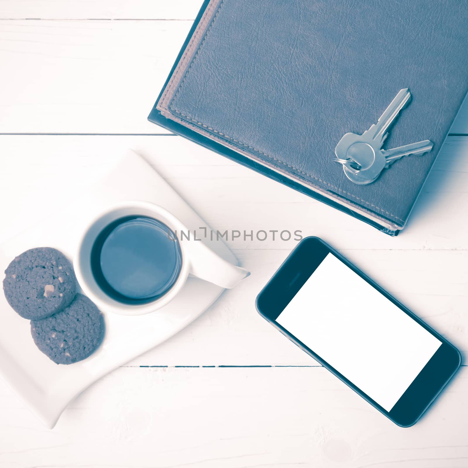 coffee cup with cookie,phone,stack of book and key on white wood table vintage style