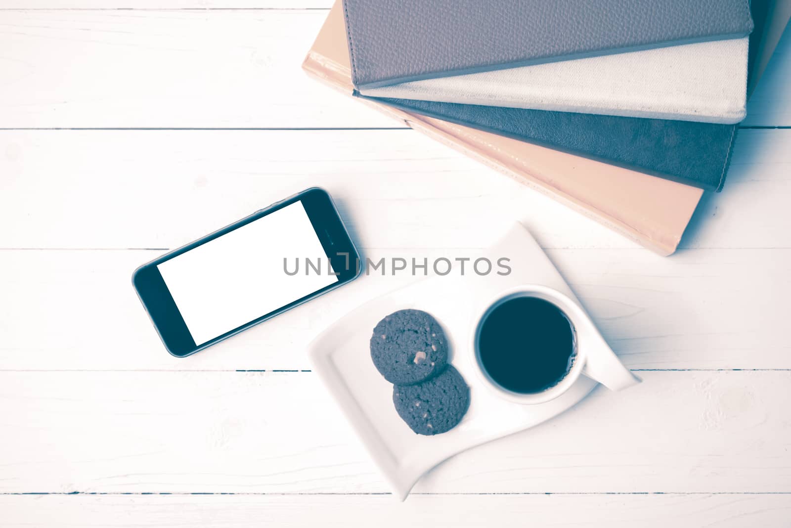 coffe cup with cookie,phone and stack of book on white wood table vintage style