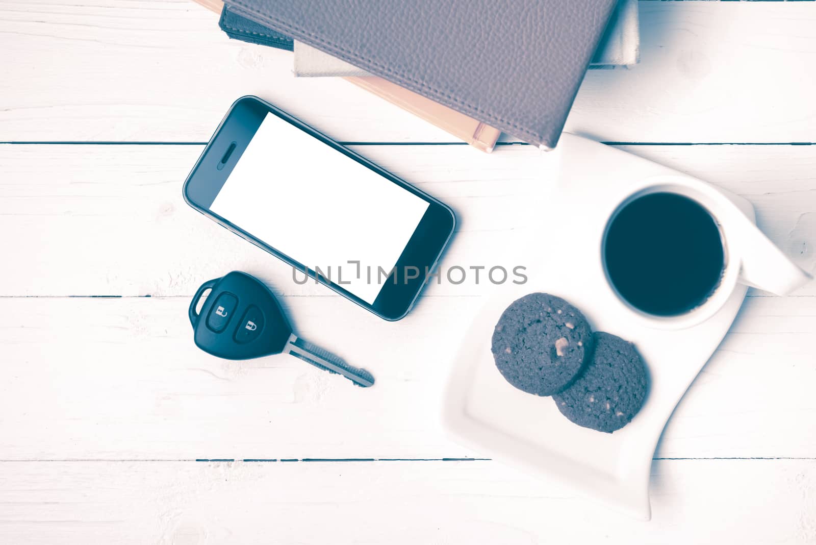 coffe cup with cookie,phone,car key and stack of book on white wood table vintage style