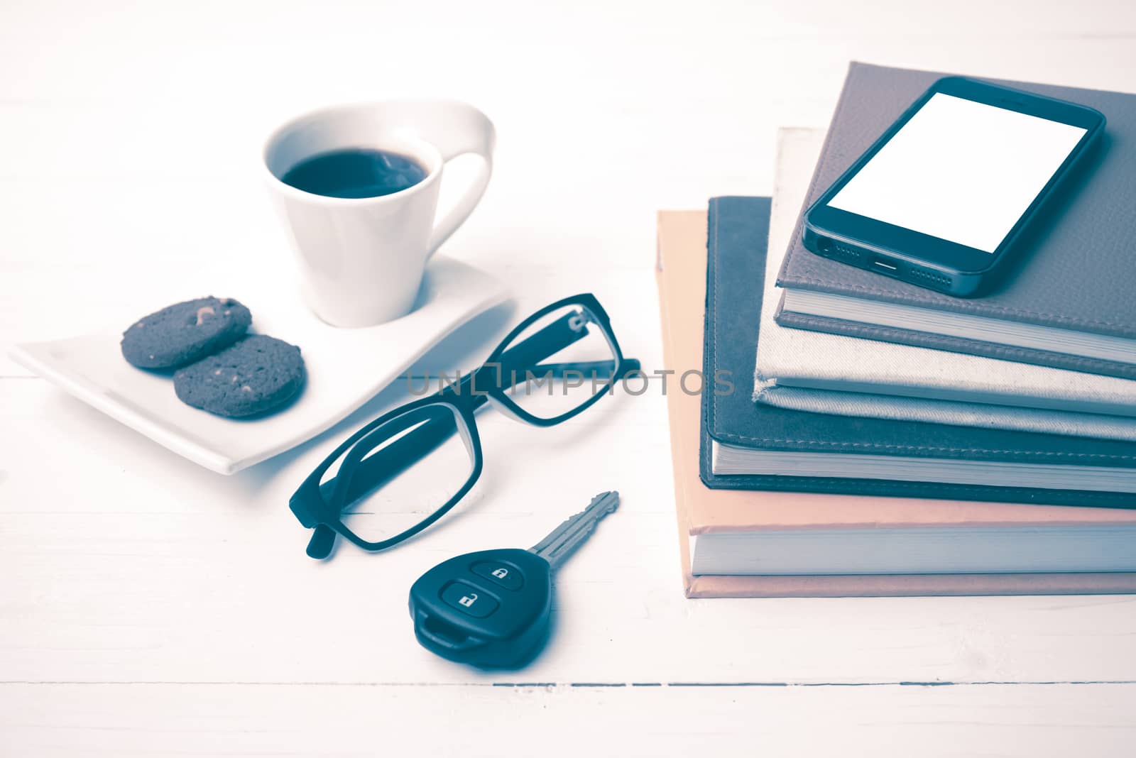 coffe cup with cookie,phone,car key,eyeglasses and stack of book on white wood table vintage style