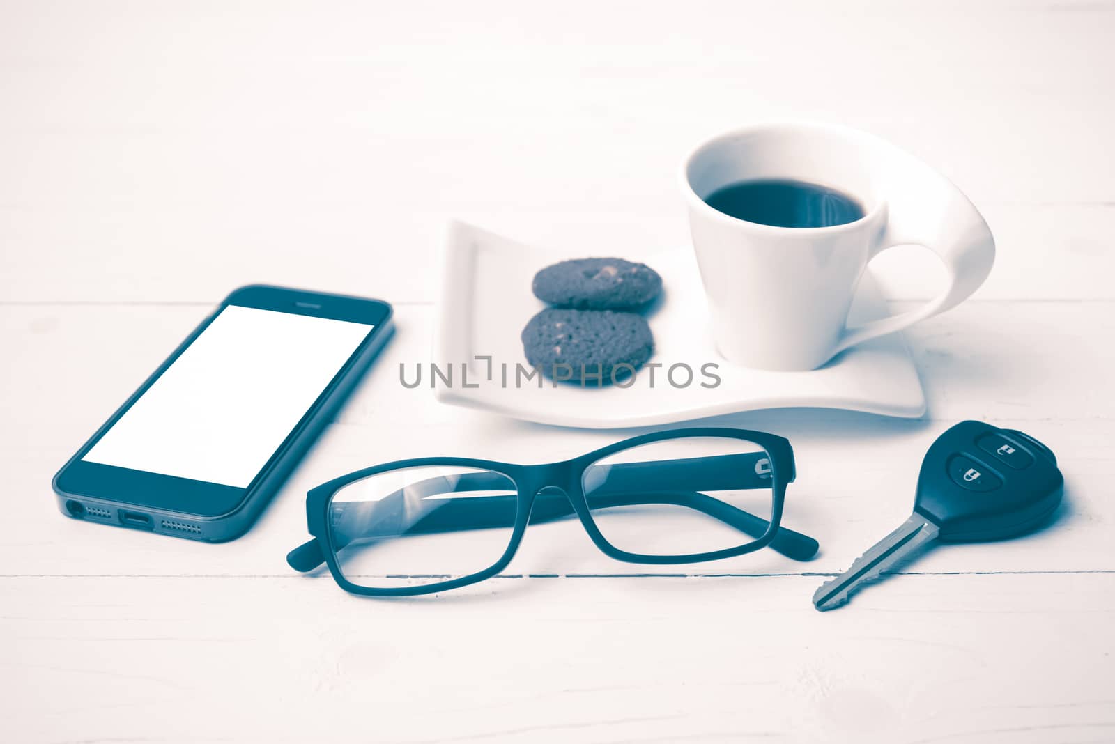 coffee cup with cookie,phone,eyeglasses and car key on white wood table vintage style