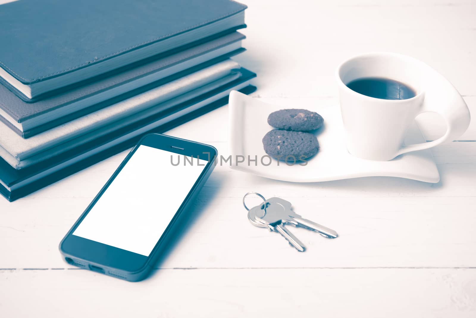 coffee cup with cookie,phone,stack of book and key on white wood table vintage style