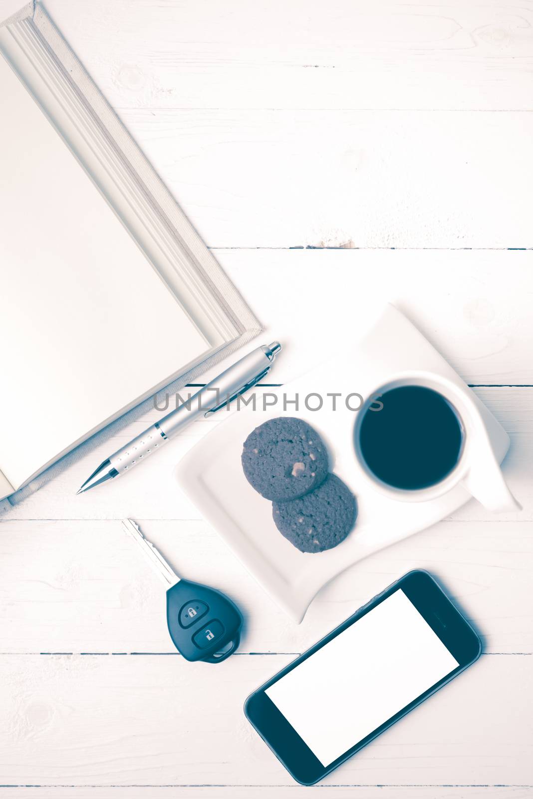 coffee cup with cookie,phone,open notebook and car key on white wood table vintage style