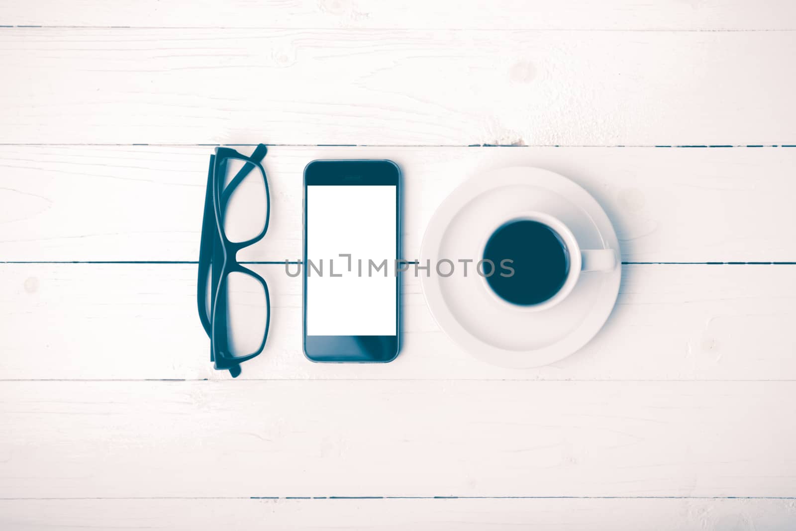 coffee cup with phone and eyeglasses on white wood table vintage style